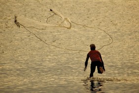 A fisherman net casting on New Caledonia's lagoon.